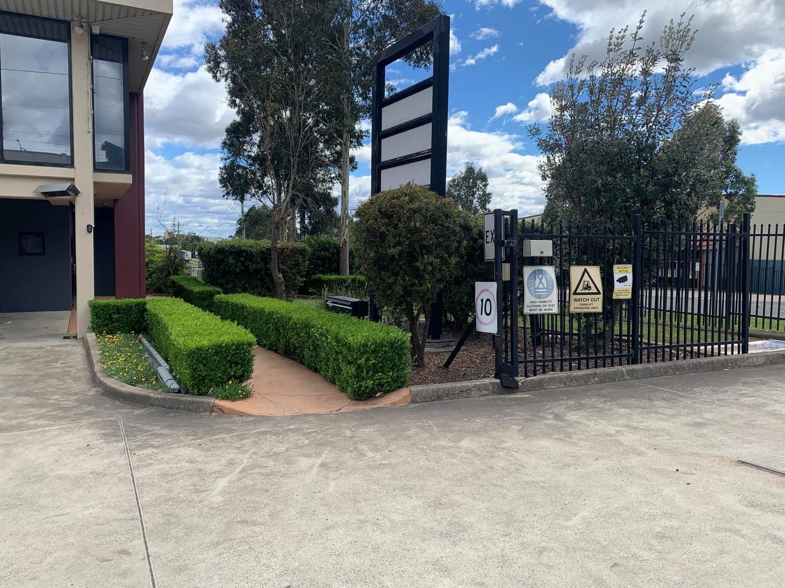 Neatly trimmed hedges framing the entrance to an industrial property